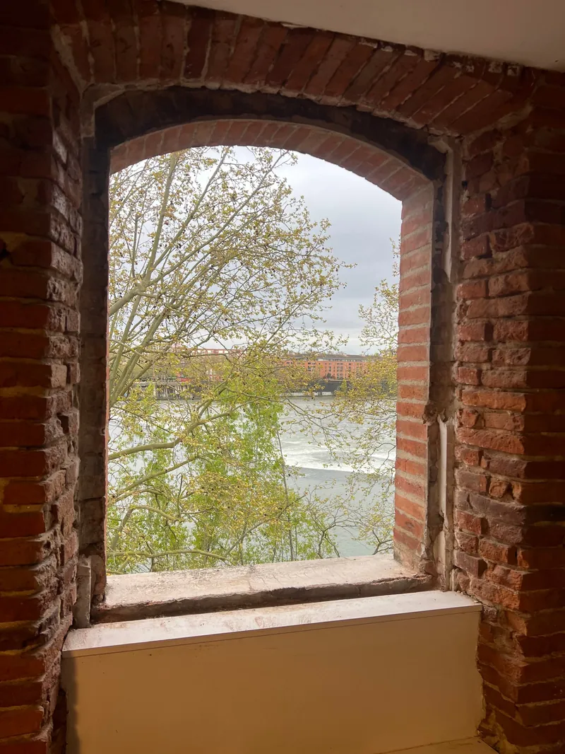 Fenêtre en briques cintrée avec vue sur paysage