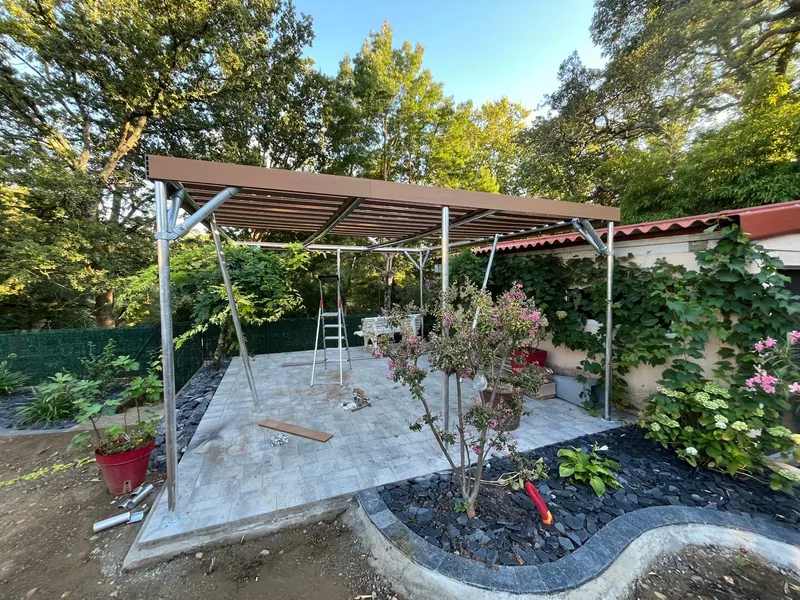 Pergola terminée avec structure aluminium et toit à lamelles motorisées au-dessus du patio avec plantes et mobilier