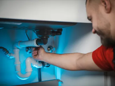 Plombier français installant une nouvelle tuyauterie dans une salle de bain à Tournefeuille